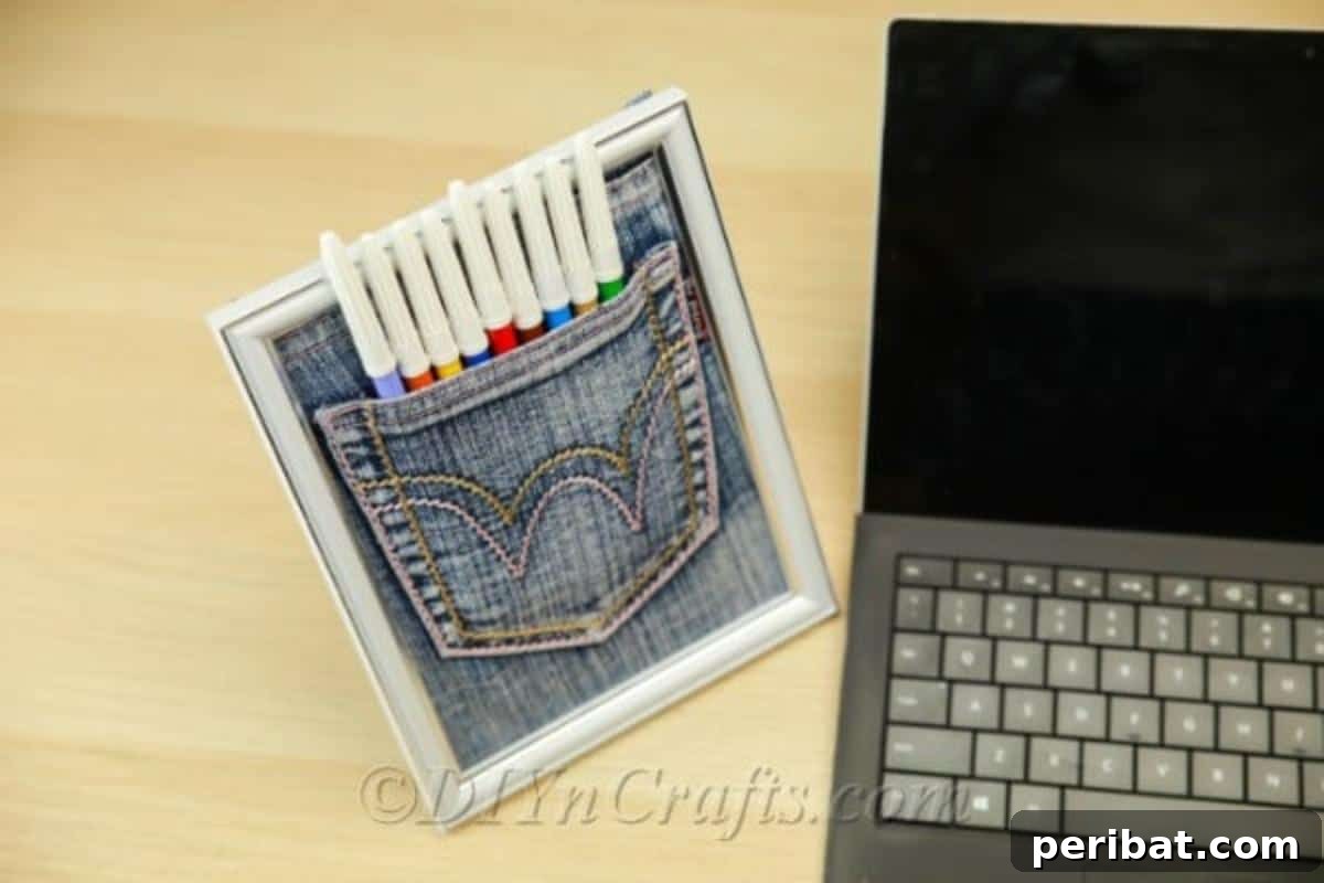 Completed denim pen pocket organizer in a frame next to a laptop
