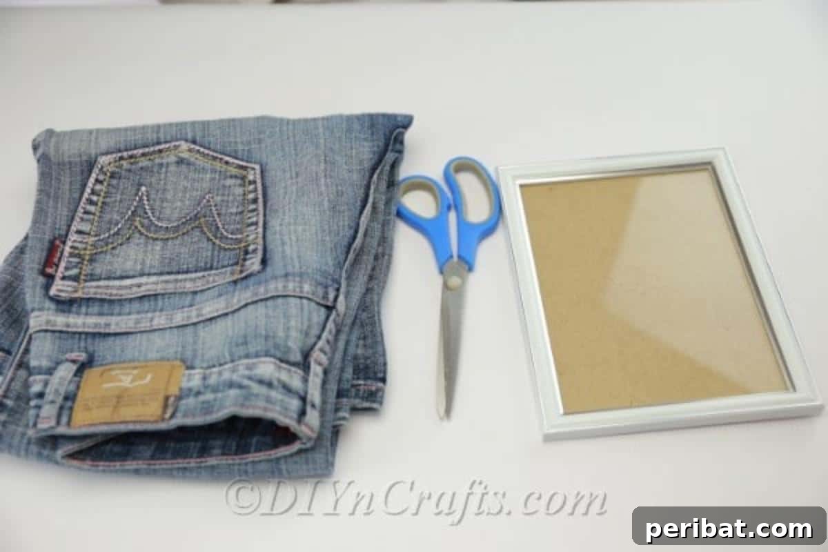 Supplies needed to make a denim pen holder, including old jeans, scissors, and a picture frame