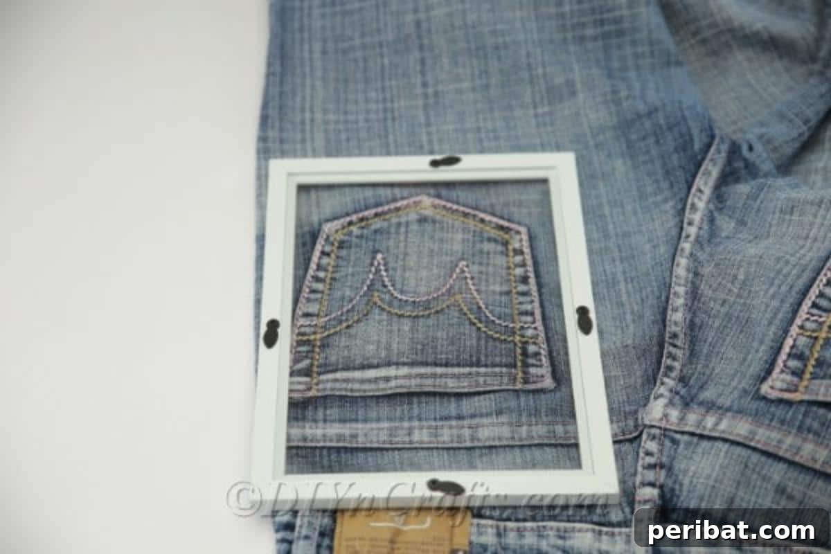 Measuring a picture frame against a denim pocket to ensure a perfect fit for a DIY organizer
