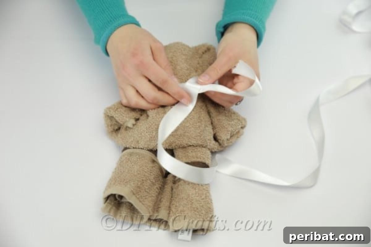 Craft a Cuddly Washcloth Bear 13 Tying ribbon around the neck of a washcloth teddy bear for decoration