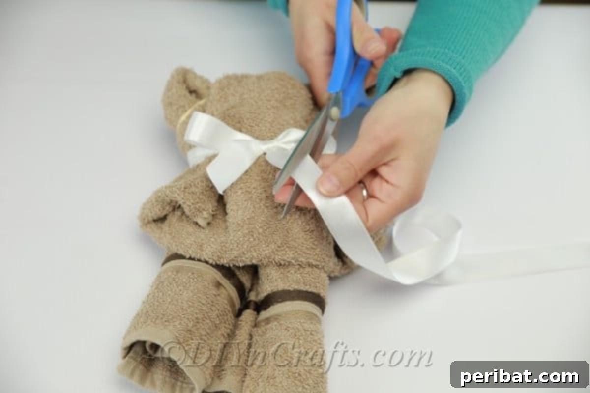 Craft a Cuddly Washcloth Bear 14 Trimming ribbon on a washcloth teddy bear, showcasing the completed craft