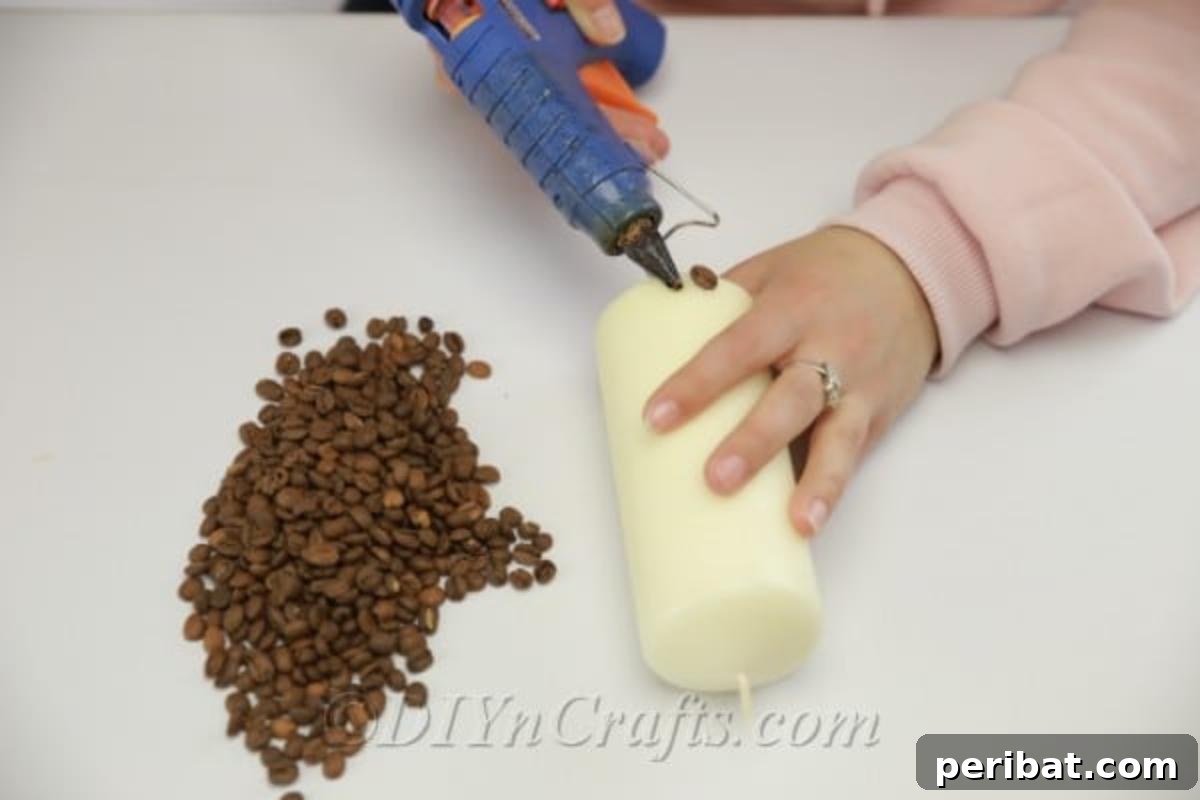 Carefully adding whole coffee beans to the base of a large pillar candle, showcasing the start of the DIY coffee bean candle creation process.