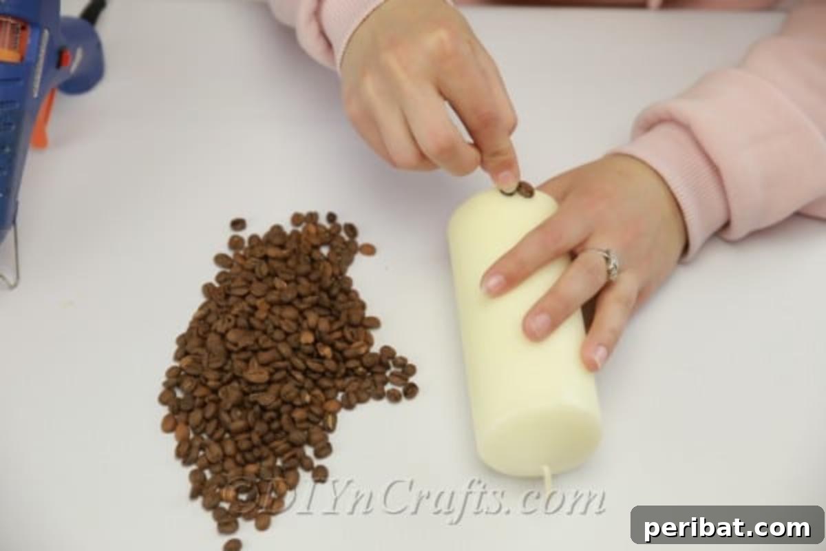 Close-up of the initial step, demonstrating how to attach coffee beans to the bottom of a candle, forming the foundation of the design.