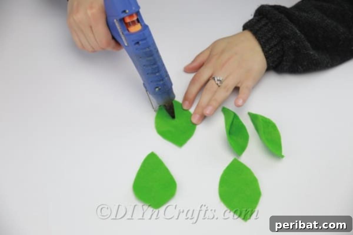 Pinching the glued ends of green felt to form three-dimensional leaves for the fabric flowers.