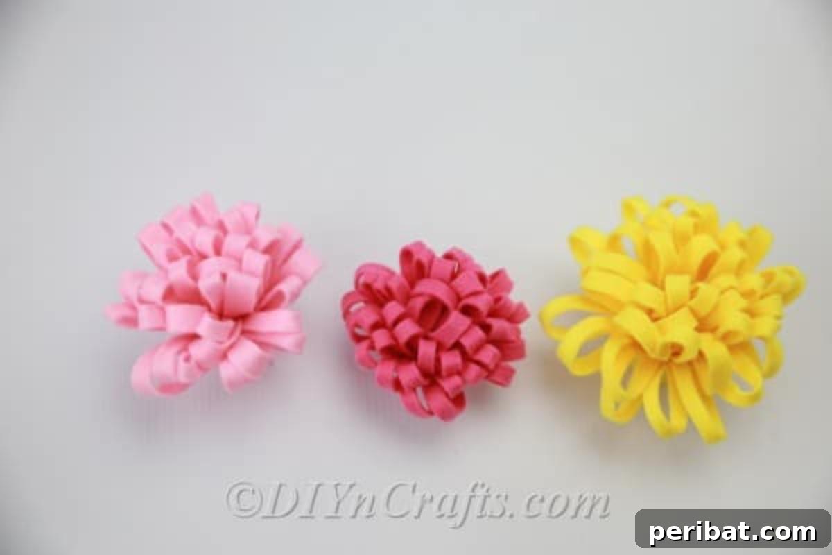 A cluster of finished DIY fabric flowers in red, yellow, and pink, showcasing their intricate petal design.