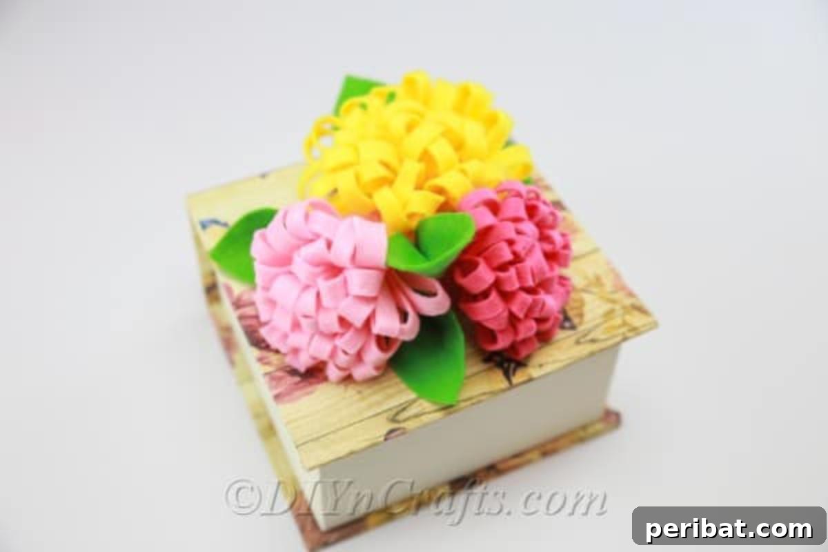 A delightful arrangement of DIY fabric flowers in red, yellow, and pink, beautifully complemented by green leaves.