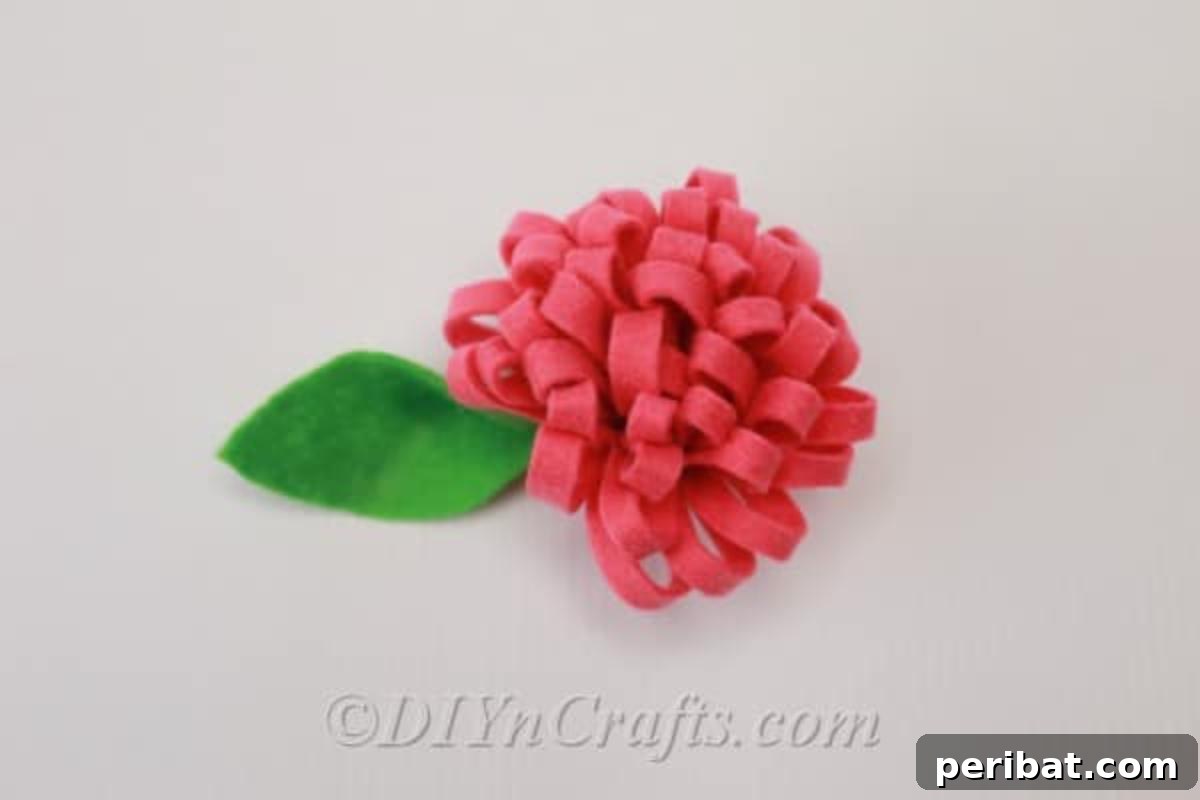 A vibrant red fabric flower, neatly crafted from felt, showcasing its delicate petals.