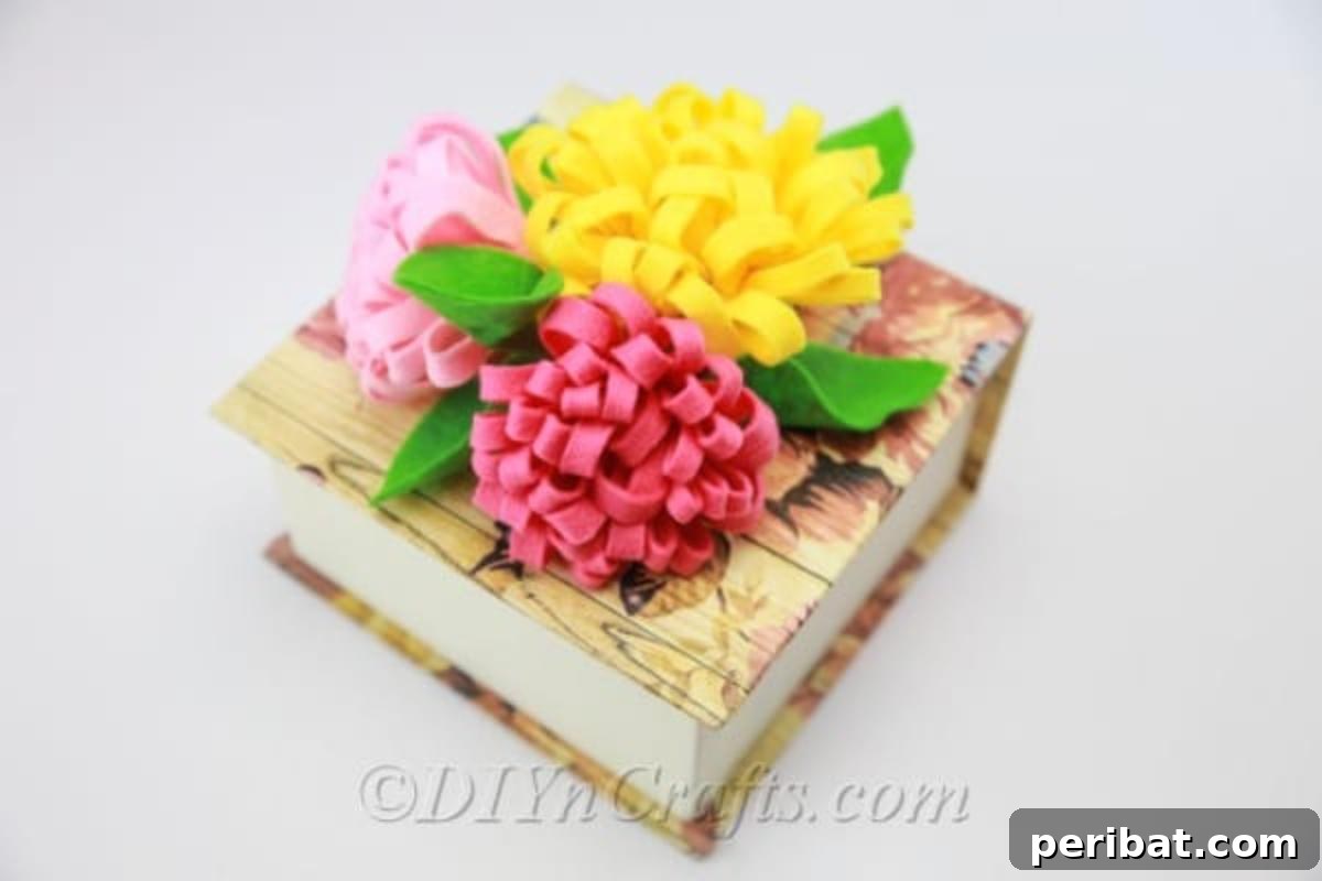 Handmade fabric flowers in various colors resting on top of a decorative box.