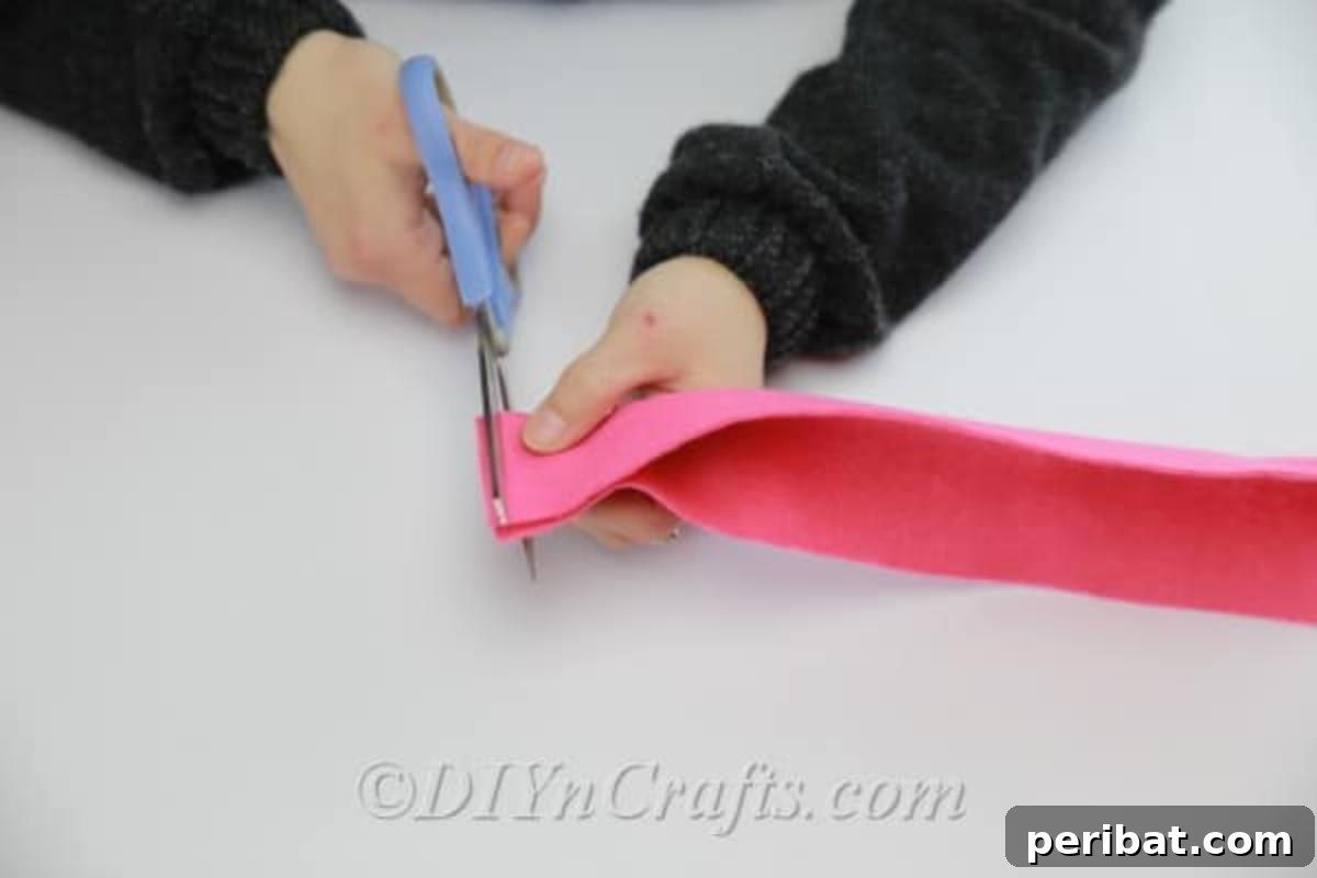 Using scissors to cut fringe-like lines into a folded piece of felt fabric, avoiding the folded edge.