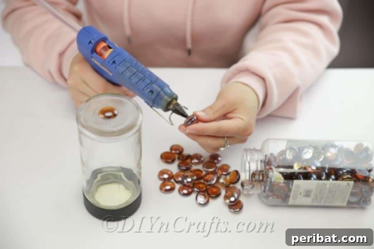 DIY Enchanted Garden Jars 7 Gluing brown decor stones onto a glass jar