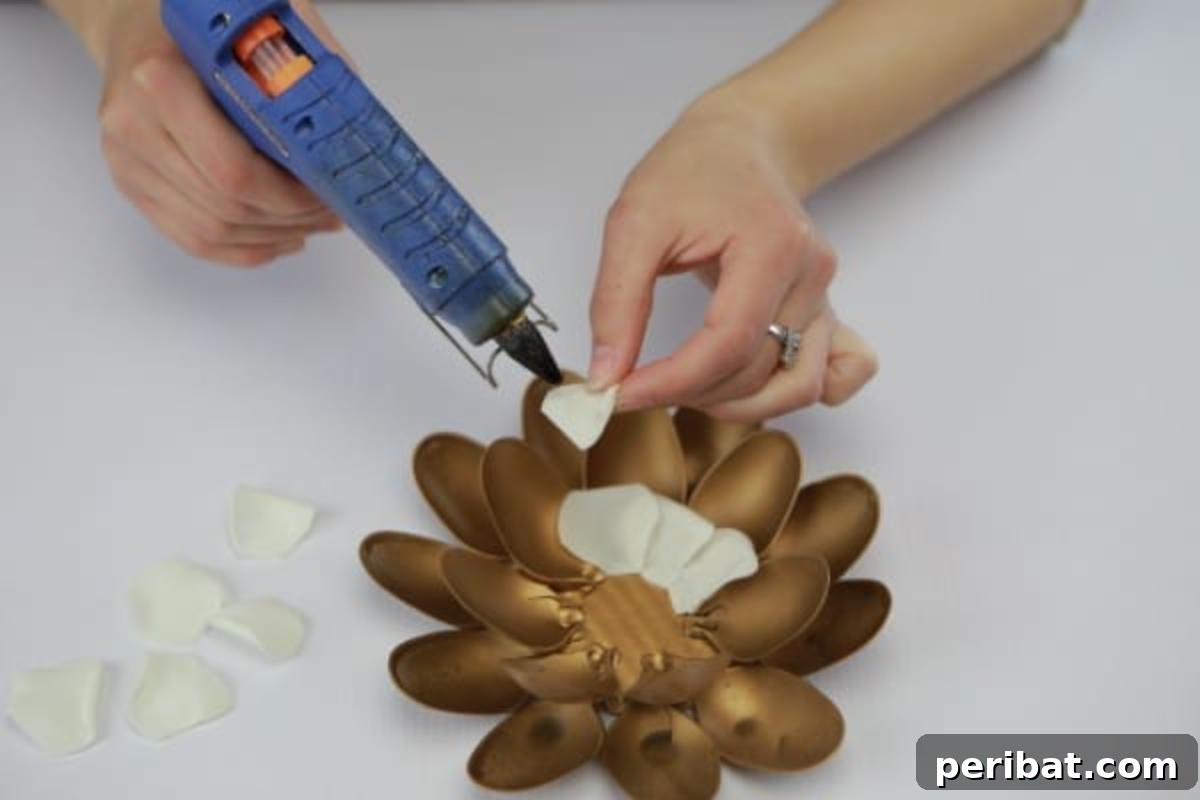 Gluing faux flower petals into the center of the spray-painted base