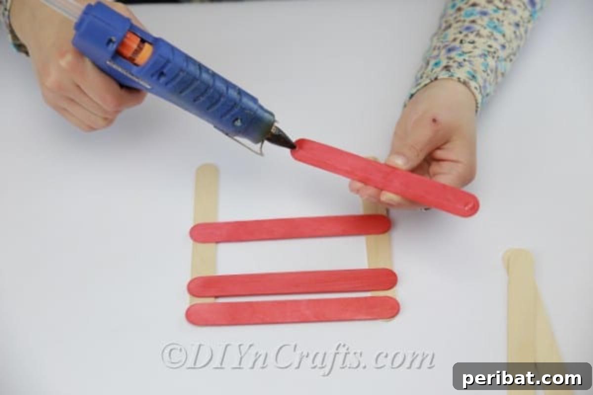 Stick-tacular Creations: 3 Crafts for Every Generation 8 Applying hot glue to the colored popsicle sticks for the earring holder
