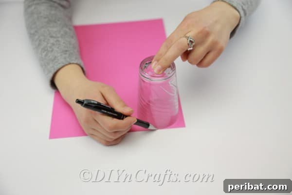 A hand tracing a circular template onto a piece of colorful cardstock paper using a pen.