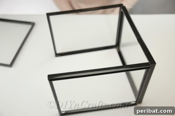 The square base of the DIY greenhouse, made from four large picture frames, stands complete and ready for the roof.