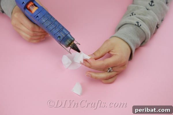 A fully assembled fabric flower base, showcasing all four folded petals symmetrically glued around the central point.