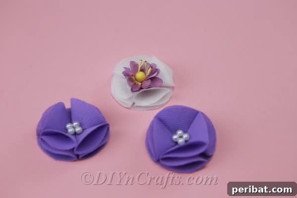 A cluster of three beautifully crafted fabric flowers, complete with pearl centers, awaiting attachment to a headband.