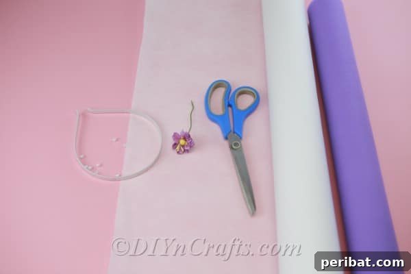 Crafting supplies neatly laid out, including colorful fabric scraps, scissors, and a hot glue gun, essential for starting your DIY flower headband project.