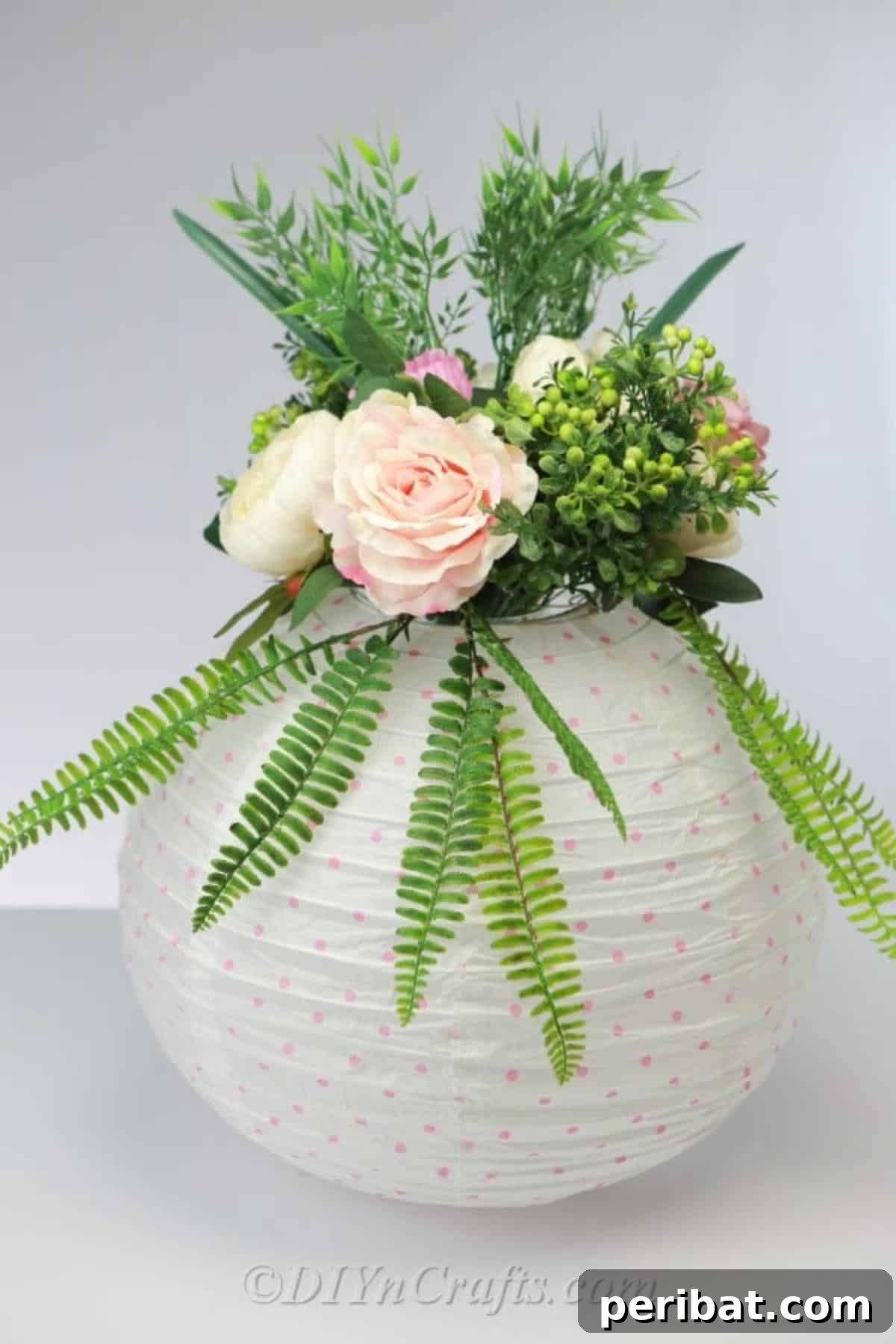 Create a Glowing Floral Lantern Centerpiece 2 A beautifully arranged paper lantern centerpiece adorned with a mix of vibrant fresh flowers and lush greenery, ready to enhance any room or event.