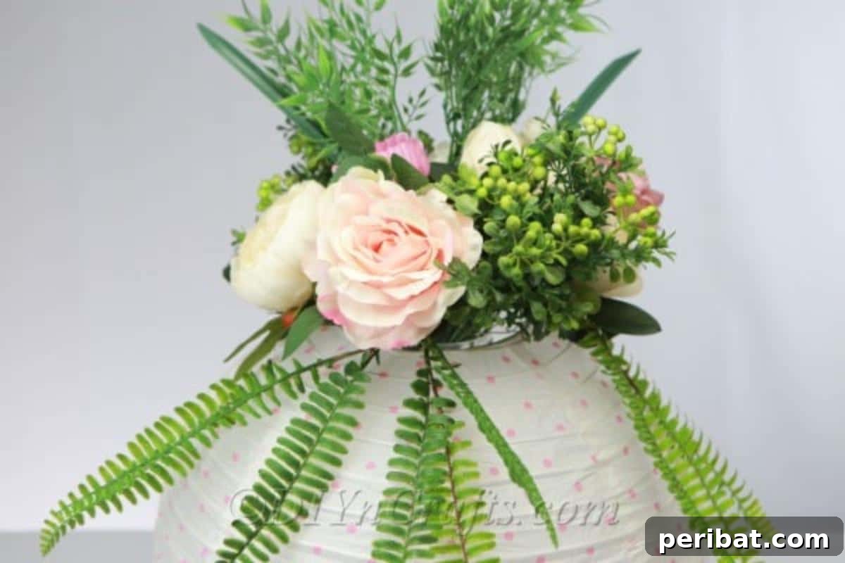 Create a Glowing Floral Lantern Centerpiece 9 A closer view of the paper lantern centerpiece, highlighting lush roses and elegant fern leaves, creating a harmonious and vibrant floral display.