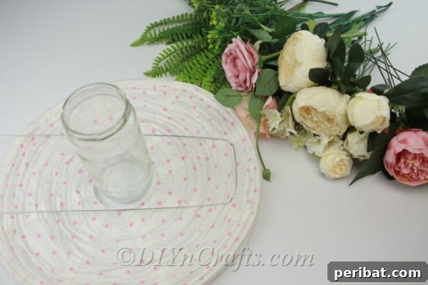 Supplies needed for a DIY paper lantern centerpiece including a paper lantern, glass jar, and various flowers and greenery.