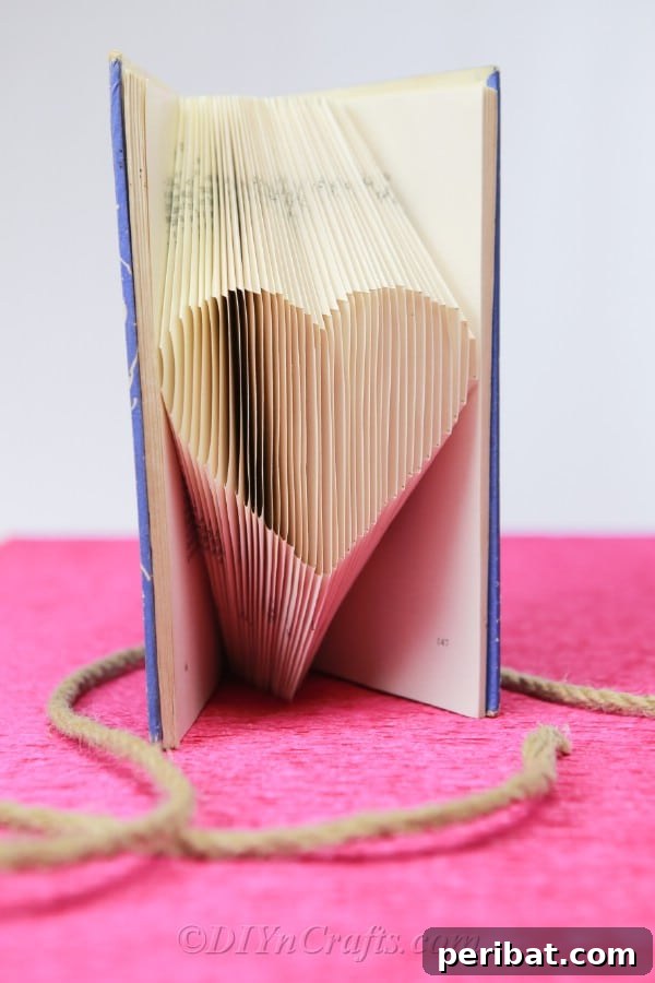 The completed book art, showcasing a perfectly formed heart shape made from folded book pages.