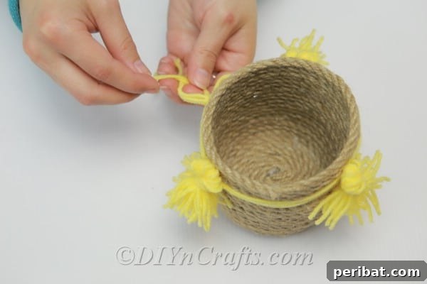 DIY Rope Baskets Elevate Your Storage Style 14 Gluing the finished yarn tassels onto the exterior of the rope basket for decoration.