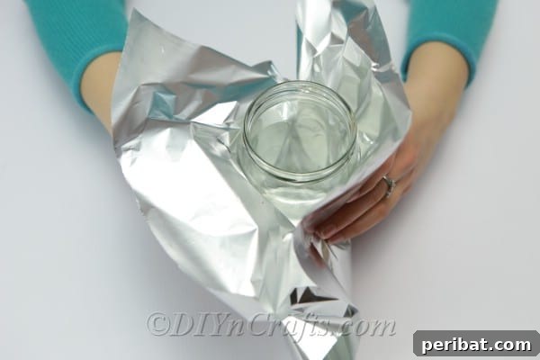 DIY Rope Baskets Elevate Your Storage Style 7 Smoothly covering an empty jar with aluminum foil to prepare it for rope wrapping.