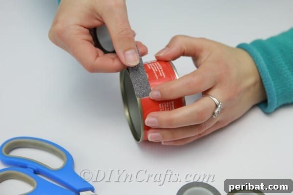 Transform Tuna Cans into Pretty Tealight Holders 6 Wrapping an empty tuna can with Washi tape, demonstrating the decoration process.
