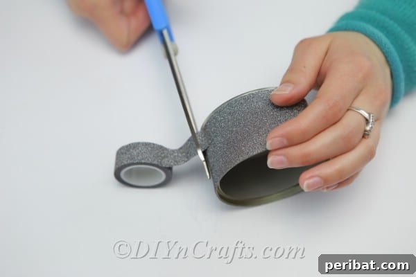 Transform Tuna Cans into Pretty Tealight Holders 7 Covering a tuna can with decorative tape, ensuring full coverage.