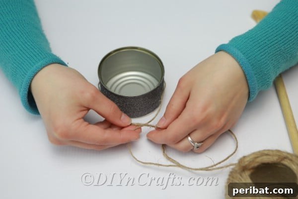 Transform Tuna Cans into Pretty Tealight Holders 8 Cutting twine to hang tuna cans, an essential step in the assembly.