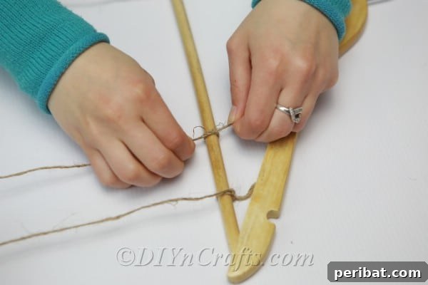 Transform Tuna Cans into Pretty Tealight Holders 9 Tying twine onto wooden clothes hanger, showing the secure attachment.
