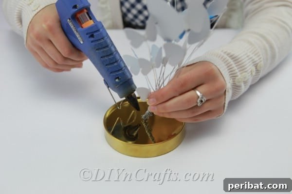 Crafting an Enchanting Butterfly Jar Terrarium 15 Applying hot glue to the jar lid to secure the bundle of wired butterflies.