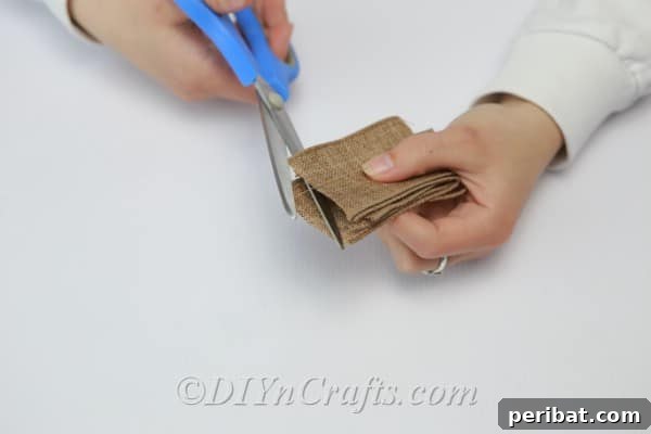 Carefully trimming the edges from burlap ribbon squares to create petal shapes for a rustic flower embellishment.