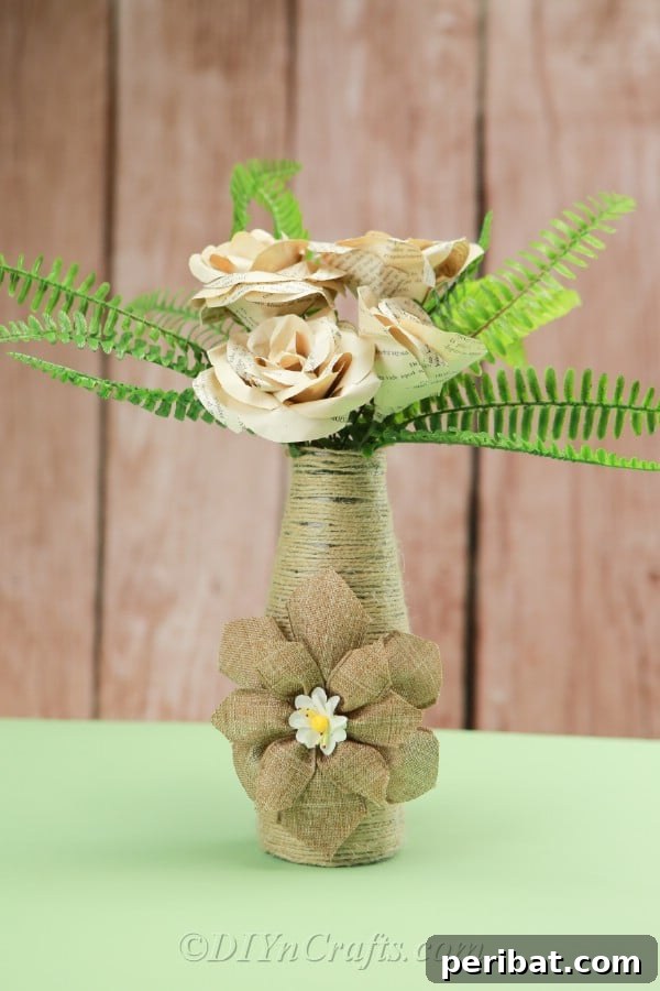 A finished rope-covered bottle vase adorned with paper flowers, ready to enhance any rustic or farmhouse decor setting.