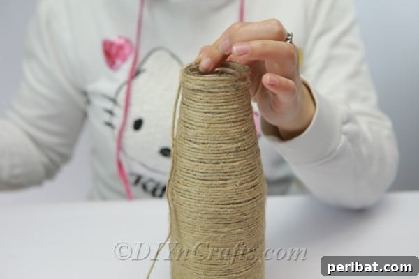 A glass bottle completely covered in meticulously wrapped twine, showcasing a finished base layer, ready for decoration.