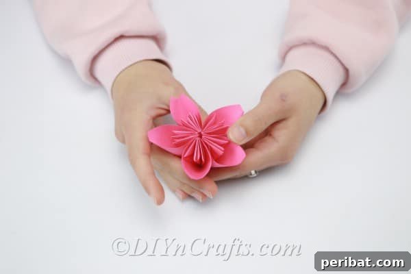 A single, perfectly formed pink paper flower with five petals, ready for embellishment