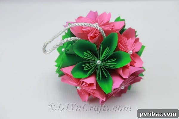 A partially assembled DIY paper flower ball, showing two halves of paper flowers being joined