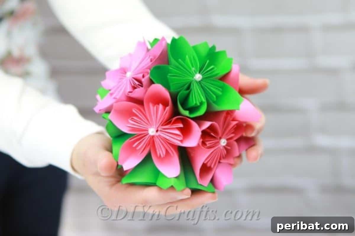 Close-up of a vibrant paper flower ball in shades of pink and green, highlighting the intricate paper folds