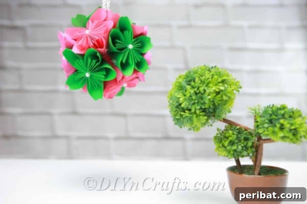 Elegant paper flower ball hanging above a small green plant, demonstrating its versatility as hanging decor