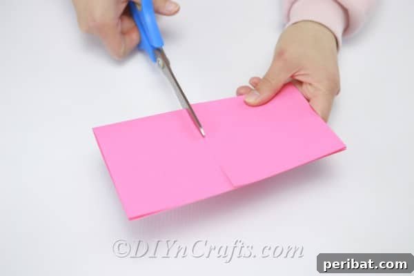 Hands carefully cutting pink paper into small, precise squares with scissors