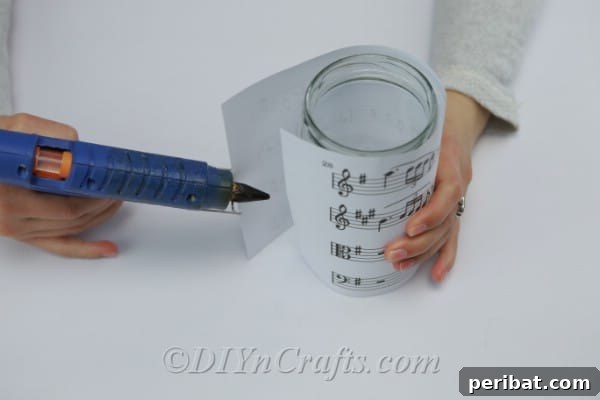 Gluing the sheet music onto the glass jar with hot glue