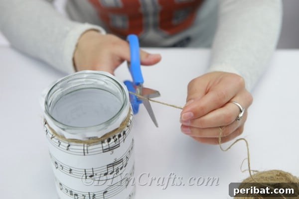 Tying rustic twine onto a glass jar for decoration