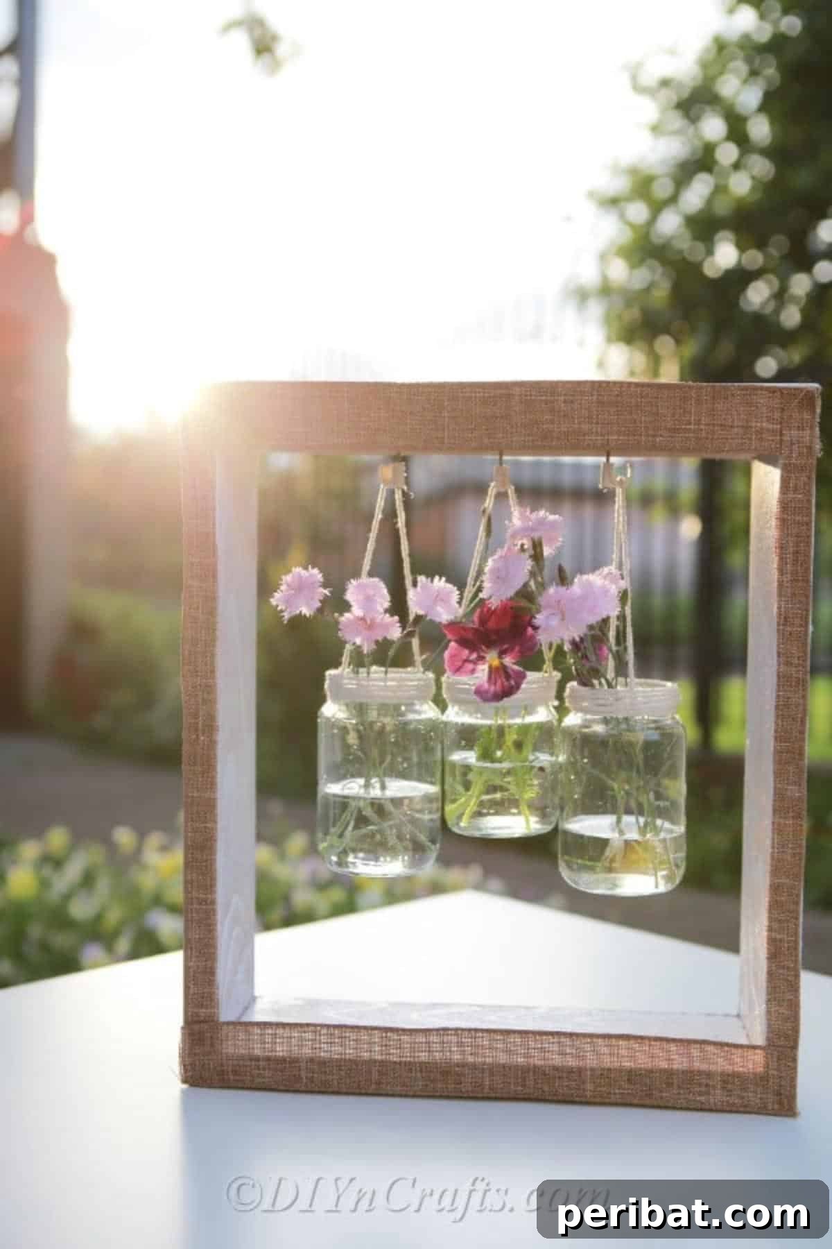 Rustic wooden box with three hanging glass jars, filled with fresh flowers, adding a touch of nature and farmhouse charm to a cozy interior.