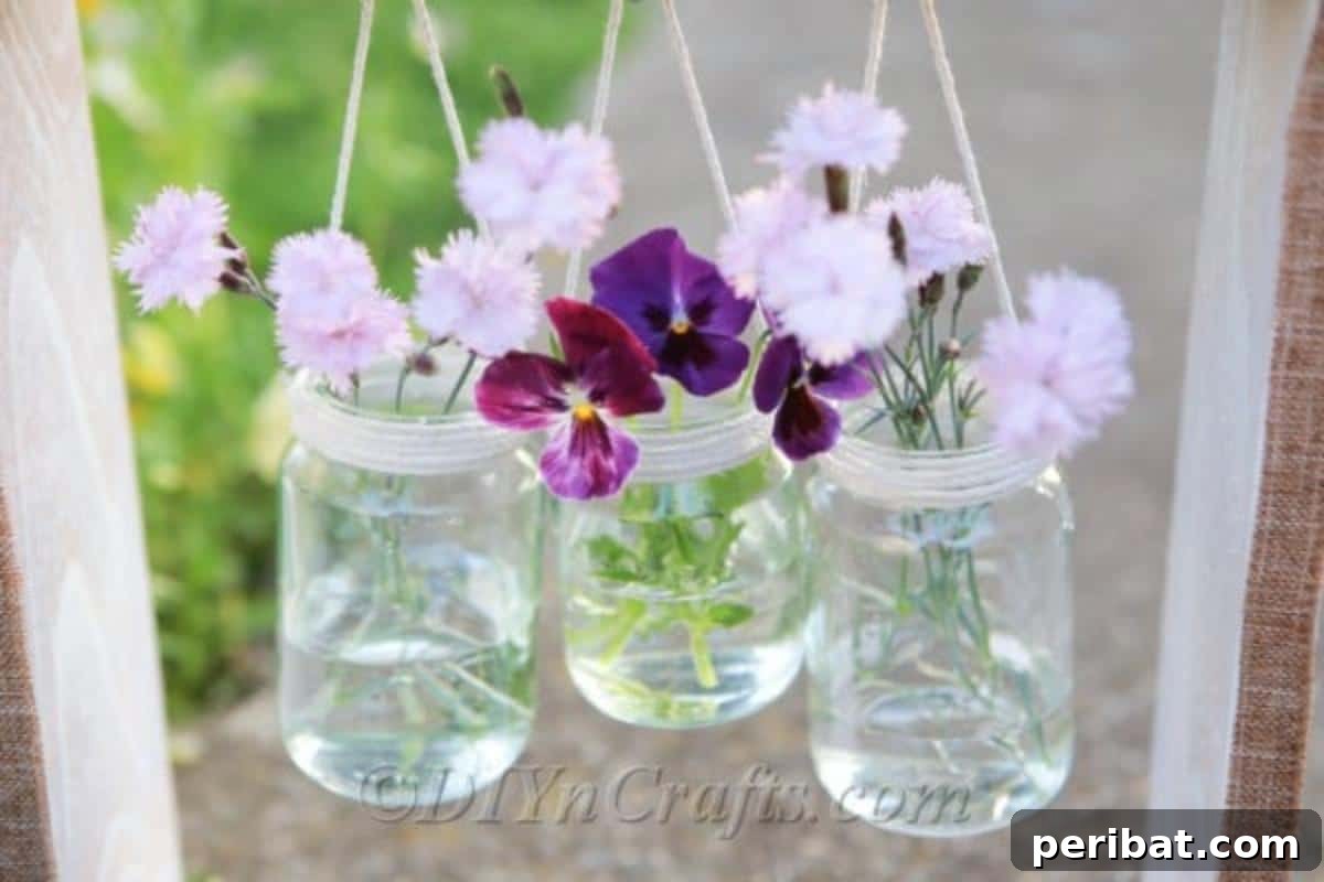 A vibrant display of pink flowers gracefully arranged in a glass jar, beautifully nestled within a rustic wooden box frame, ready for hanging.