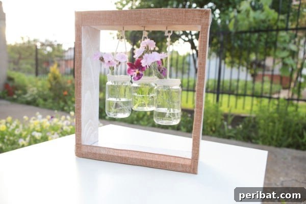 How To Make A Wooden Jar Vase Hanger - A beautifully crafted wooden box with hanging glass jars, elegantly adorned with flowers, ready to enhance any rustic or farmhouse decor.