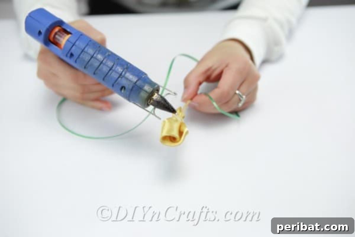 A crafter meticulously wrapping a green ribbon around a wooden dowel, creating the stem for a satin tulip.