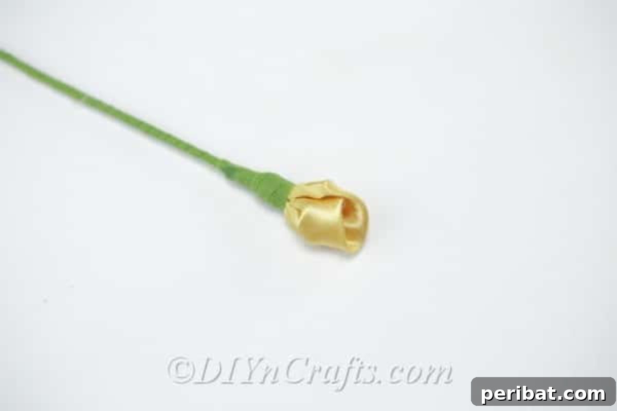 A beautifully completed yellow satin tulip with a green stem, showcasing the elegance of the handmade flower.