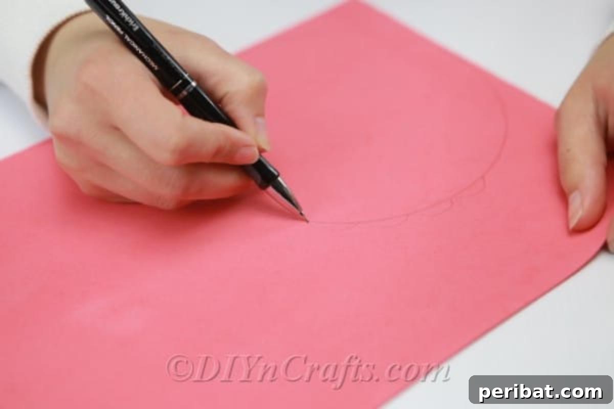A wavy, spiral line is being drawn with a pencil from the edge of a craft foam circle towards its center, creating a unique pattern.