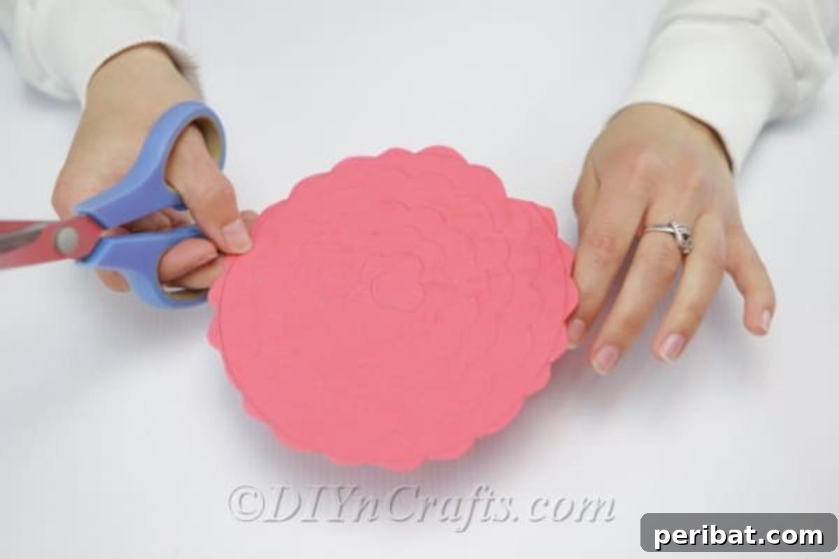 A crafter cutting along a wavy line drawn on craft foam, creating a continuous spiral strip.
