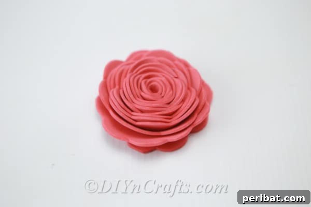 A fully formed pink flower crafted from foam, showcasing the successful completion of the rolling technique.